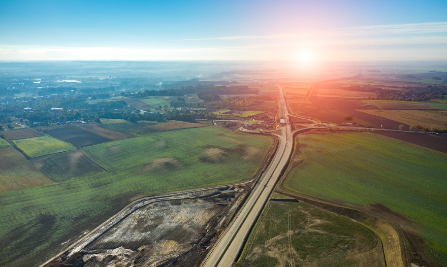 Birds eye view image of a road between fields showing infrastructure benefits stock image CTA element